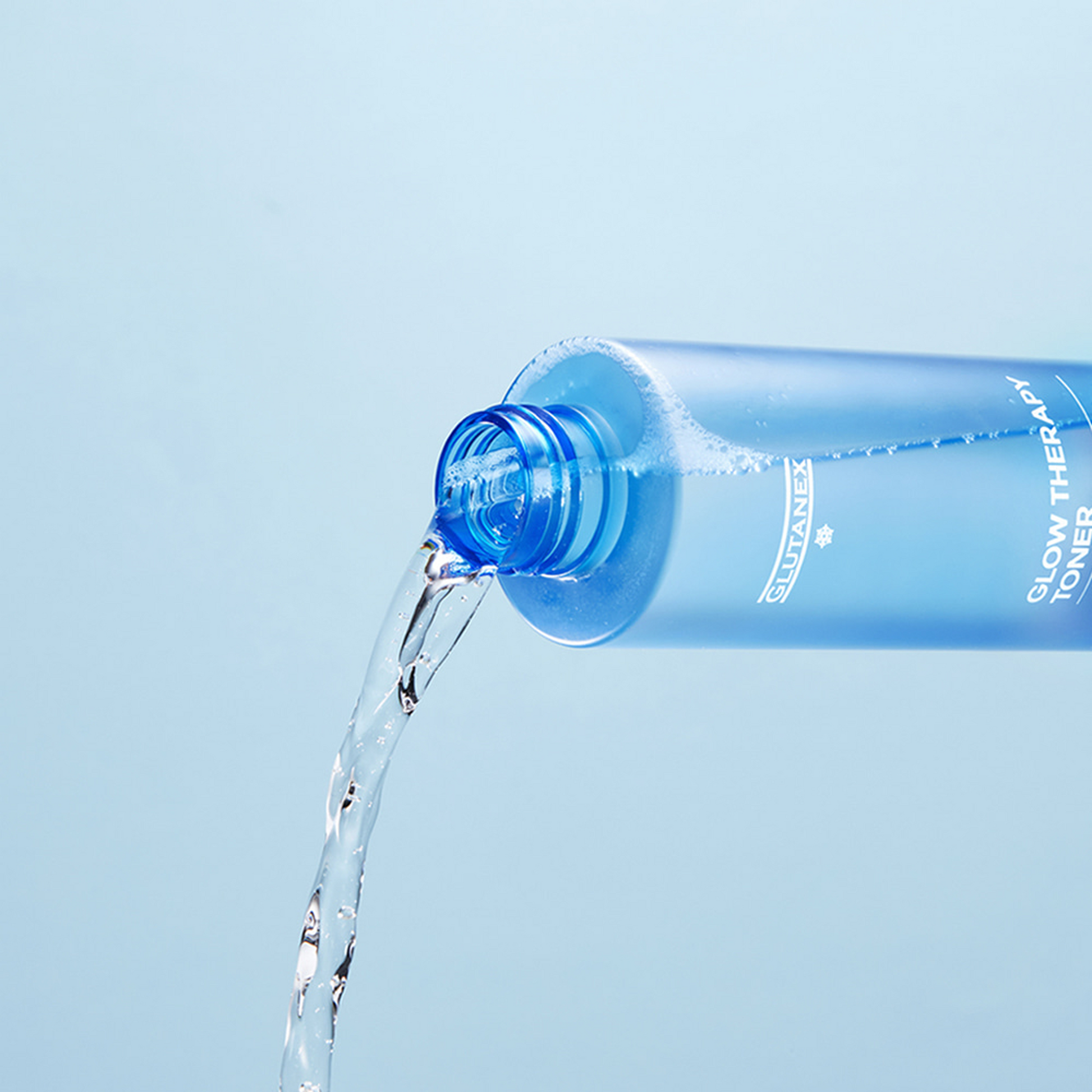 Blue bottle of skincare product being poured on a light blue background
